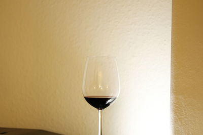 Close-up of wine glass on table against wall