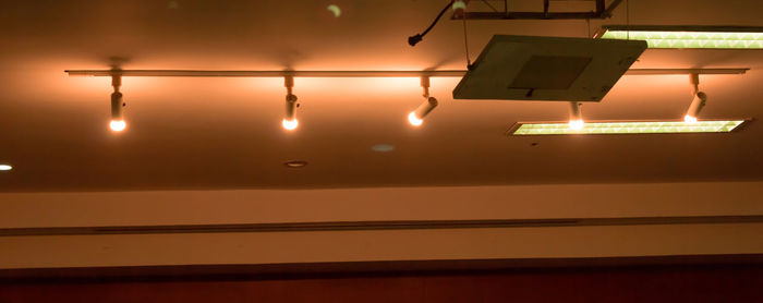 Low angle view of illuminated lighting equipment hanging at night