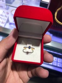 Close-up of human hand holding ring in jewelry box