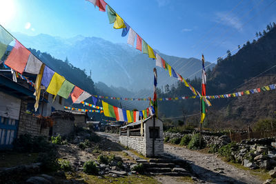 Multi colored flags hanging on mountain against sky