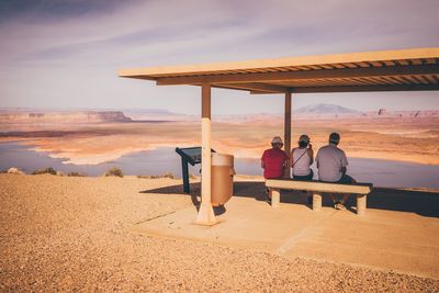 Rear view of friends sitting on seat against landscape