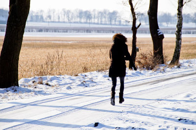 Full length of woman walking on snow covered field