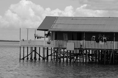 Wooden posts on pier by sea against sky