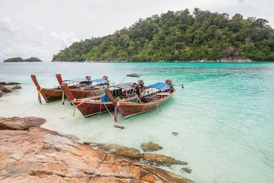 People in boat on shore against sky