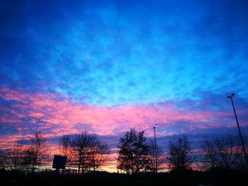 Low angle view of silhouette trees against dramatic sky
