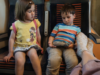 Two siblings watching a movie in a smartphone in a train