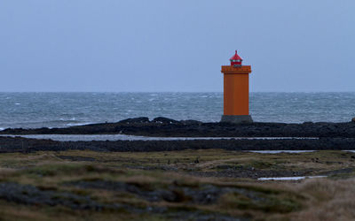 Lighthouse by sea against sky