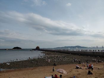 People at beach against sky