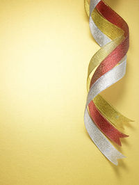 Close-up of multi colored ribbons over yellow background