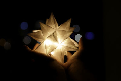 Close-up of hand holding illuminated lights at night