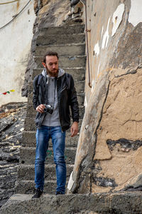 Portrait of young man standing against wall