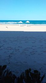 Scenic view of beach against clear blue sky