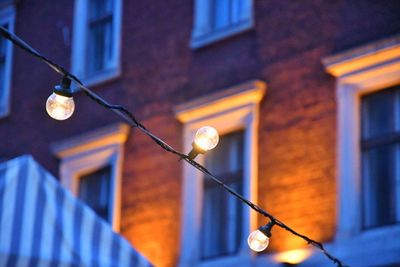 Low angle view of light bulbs hanging on building