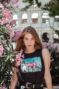 Portrait of beautiful woman standing against pink flowering plants