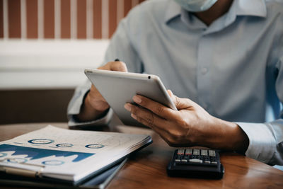 Midsection of man using smart phone on table