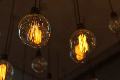 Low angle view of illuminated light bulbs hanging from ceiling