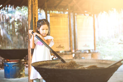 Girl mixing animal dung in container at workshop