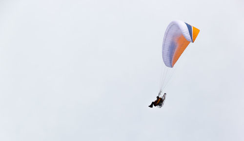 Low angle view of person paragliding against sky