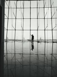 Full length of silhouette man standing by window at airport