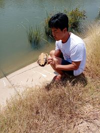 Full length of boy sitting by lake