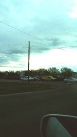 Cars on road against cloudy sky