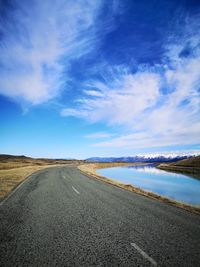 Road by land against blue sky