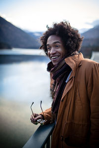 Portrait of smiling young woman standing against river