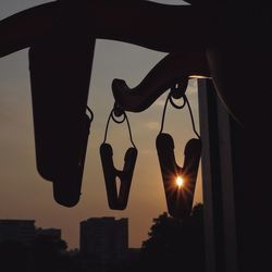 Silhouette clothespins hanging from hooks during sunset