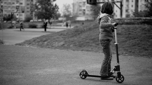 Girl with push scooter standing on road