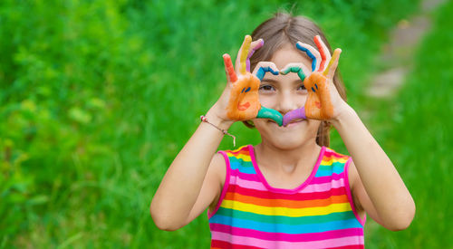 Smiling girl making heart shape with colored hands