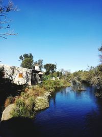 Scenic view of river and houses against clear blue sky