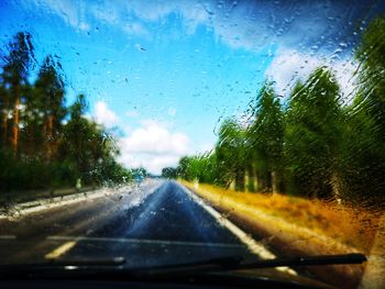 Road seen through wet windshield during rainy season