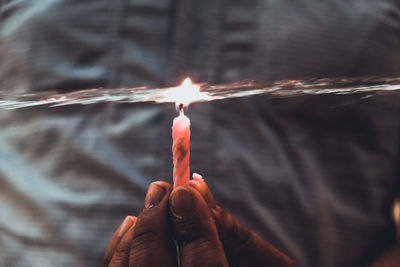 Close-up of hand holding burning candle