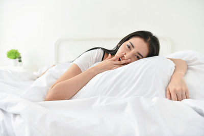 Portrait of woman lying on bed at home