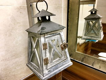 Close-up of lantern hanging on wooden wall