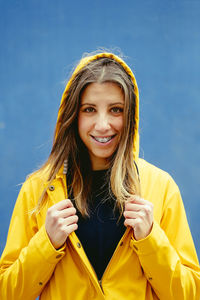 Portrait of young woman standing against blue sky