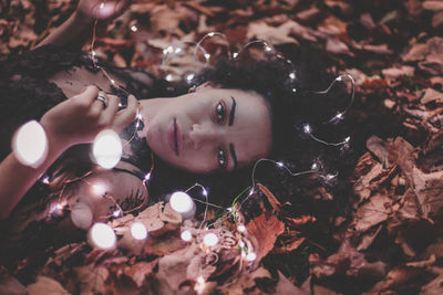 Portrait of young woman lying on field at park during autumn