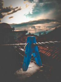 Close-up of clothespins on blue car against sky during sunset