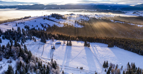 Scenic view of snow covered landscape against sky during sunset