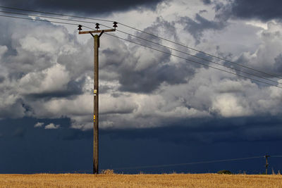 Low angle view of electricity pylon on field against sky