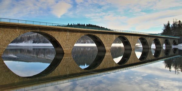 Low angle view of arch bridge over river against sky