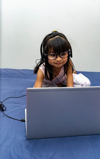 Girl using laptop on bed at home