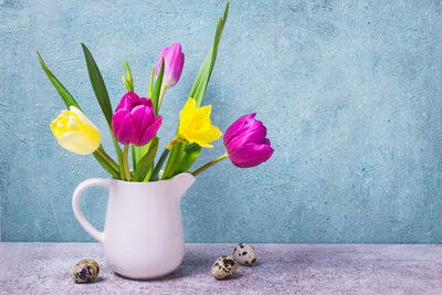 Close-up of tulips in vase on table against wall