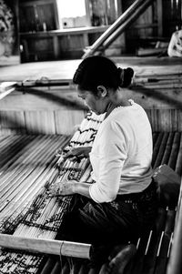 Side view of woman weaving loom in factory