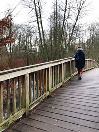 Rear view of woman standing on footbridge