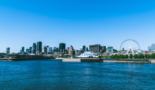 Sea by buildings against clear sky