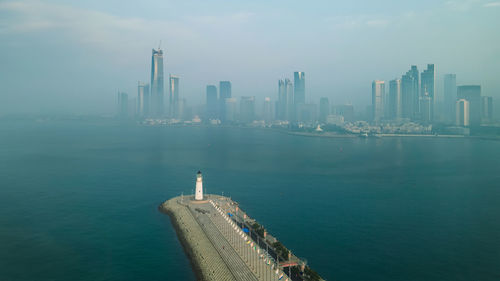 Modern buildings by sea against sky in city