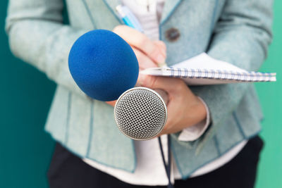 Midsection of female journalist holding microphone