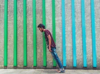 Side view of young man leaning against wall