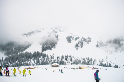 People skiing on snowcapped mountain against clear sky